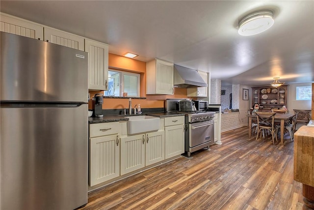 kitchen with wall chimney range hood, dark hardwood / wood-style floors, stainless steel appliances, and sink