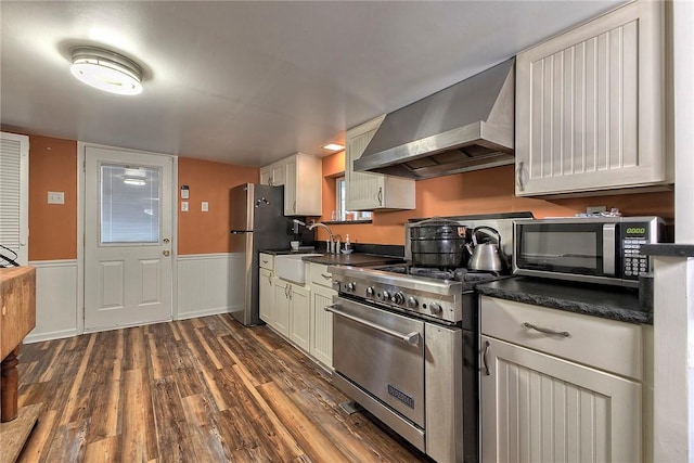 kitchen with sink, white cabinets, dark hardwood / wood-style flooring, stainless steel appliances, and wall chimney exhaust hood