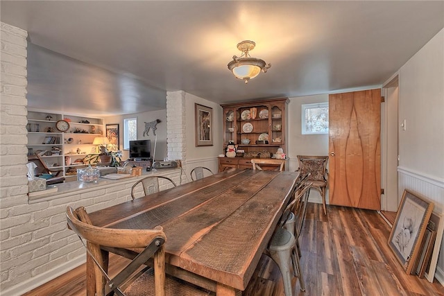 dining room with brick wall, dark hardwood / wood-style floors, and built in features