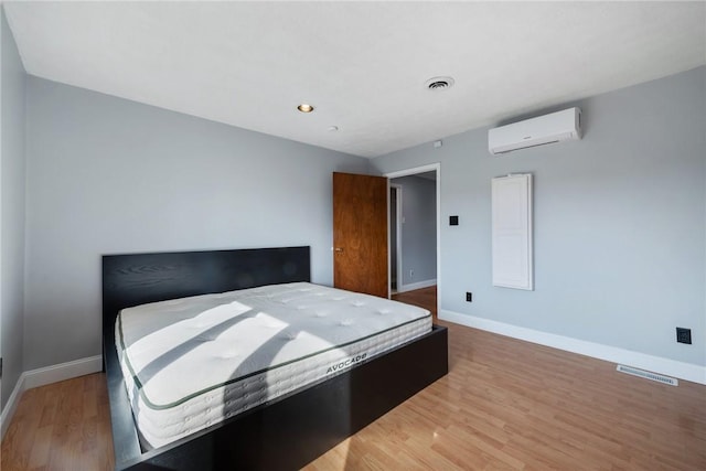 bedroom featuring a wall mounted air conditioner and hardwood / wood-style flooring