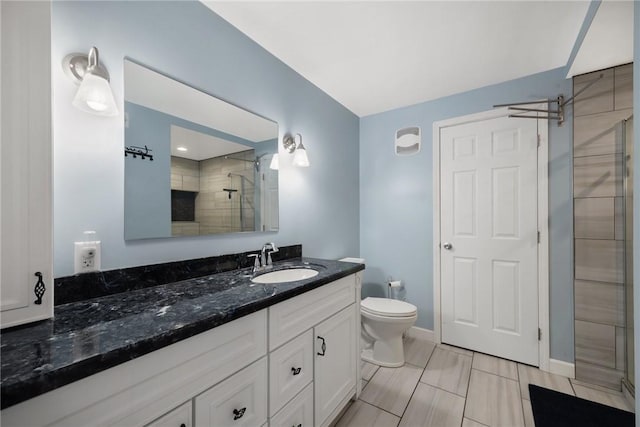 bathroom featuring a tile shower, vanity, and toilet