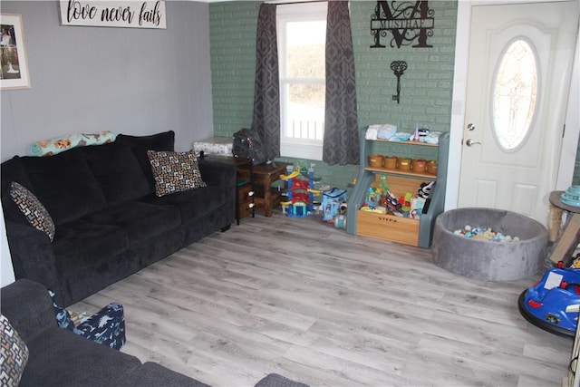 living room with brick wall and light hardwood / wood-style floors