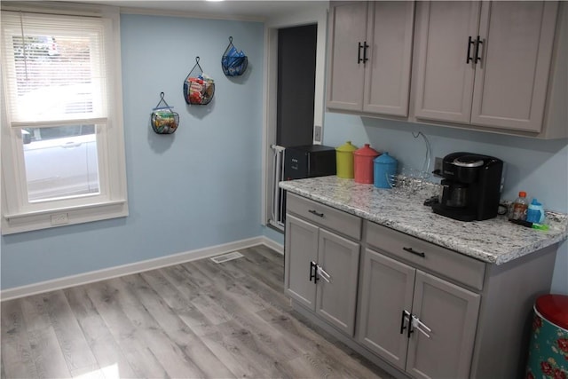 kitchen with light stone counters, light hardwood / wood-style flooring, and gray cabinets