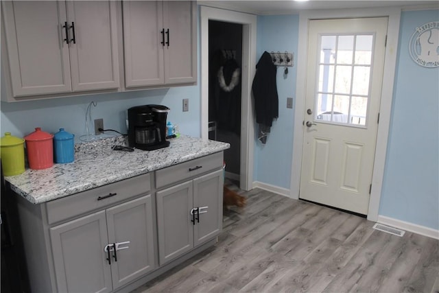 kitchen with light stone countertops, gray cabinetry, and light hardwood / wood-style floors