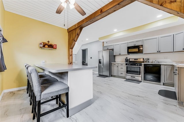 kitchen with gray cabinets, kitchen peninsula, a breakfast bar area, and black appliances