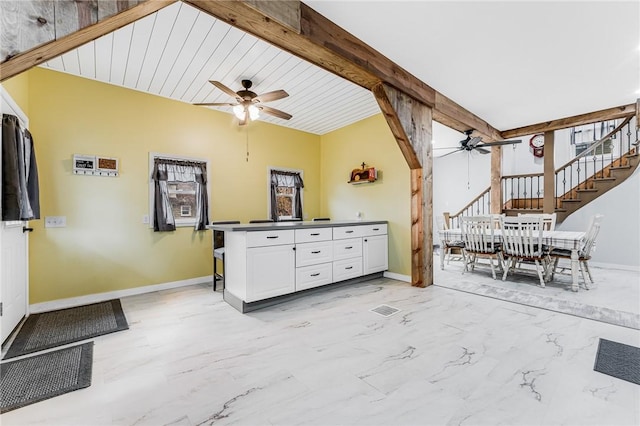 interior space featuring ceiling fan, white cabinets, and beam ceiling