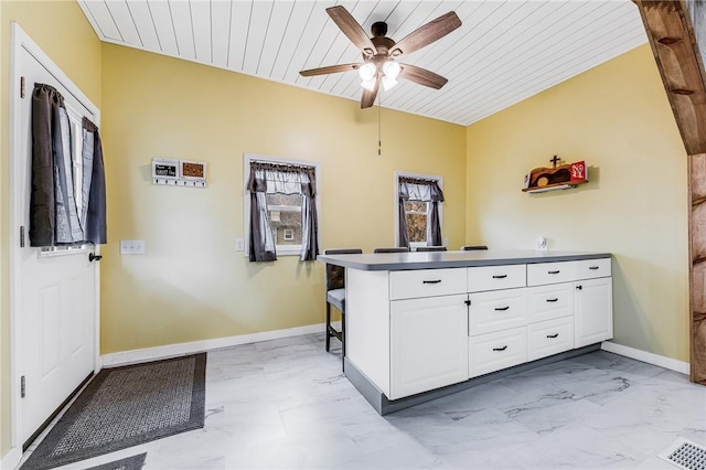 interior space with lofted ceiling, wooden ceiling, kitchen peninsula, ceiling fan, and white cabinets