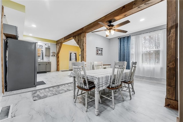 dining area featuring ceiling fan and beamed ceiling