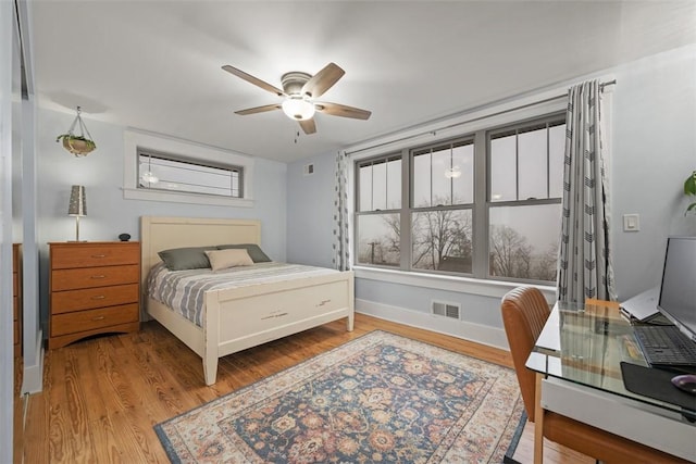 bedroom with multiple windows, hardwood / wood-style flooring, and ceiling fan