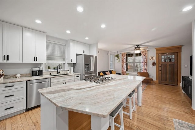 kitchen with stainless steel appliances, a center island, sink, and white cabinets