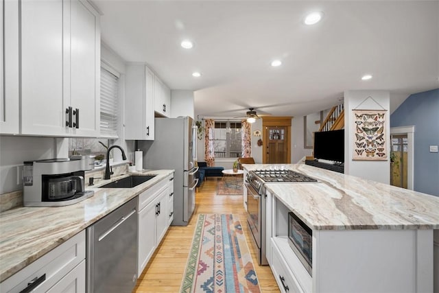 kitchen featuring sink, appliances with stainless steel finishes, light stone countertops, white cabinets, and light wood-type flooring