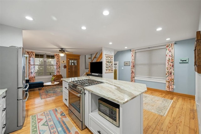 kitchen featuring a center island, light hardwood / wood-style flooring, stainless steel appliances, light stone countertops, and white cabinets