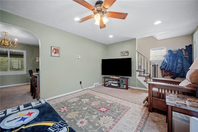 living room featuring ceiling fan with notable chandelier and carpet floors