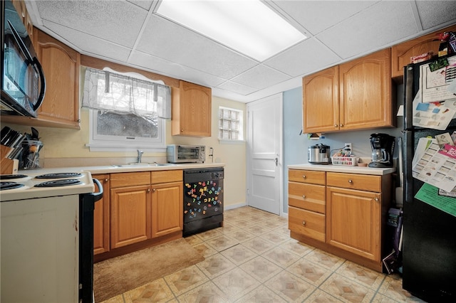 kitchen with sink, a paneled ceiling, and black appliances