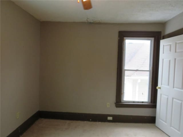 spare room with a ceiling fan and baseboards