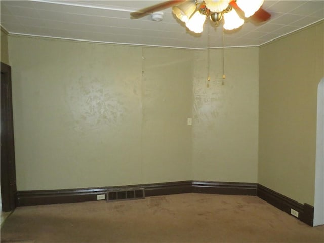 carpeted empty room with baseboards, visible vents, and a ceiling fan