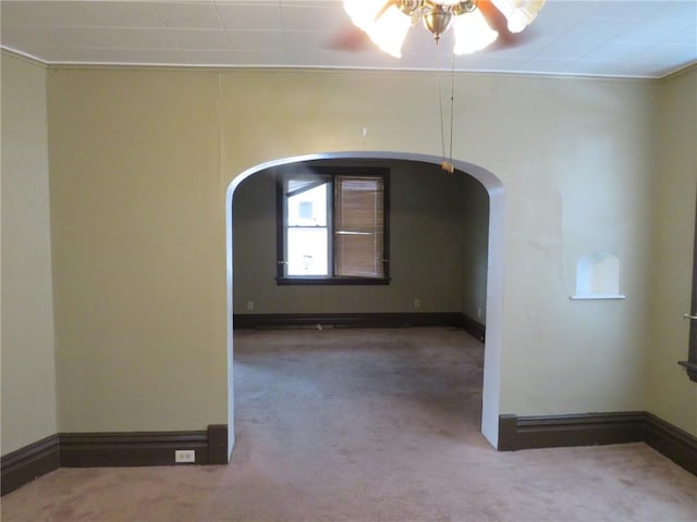 spare room featuring arched walkways, carpet flooring, and baseboards