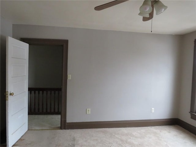 carpeted spare room featuring a ceiling fan and baseboards