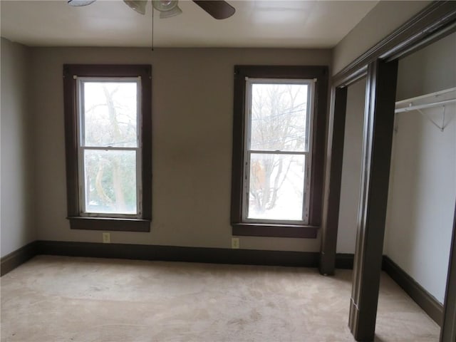 unfurnished bedroom featuring ceiling fan, light colored carpet, a closet, and multiple windows