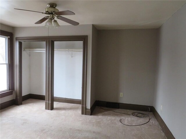 unfurnished bedroom featuring multiple windows, light carpet, a closet, and ceiling fan