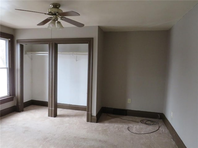 unfurnished bedroom featuring carpet, multiple windows, baseboards, and ceiling fan