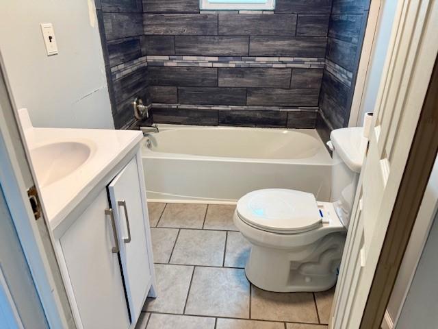 full bathroom featuring tile patterned flooring, vanity, tiled shower / bath combo, and toilet