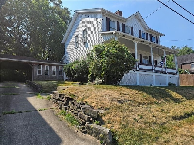 view of front of house with a carport, covered porch, and a front lawn