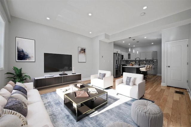 living room featuring sink and light hardwood / wood-style floors