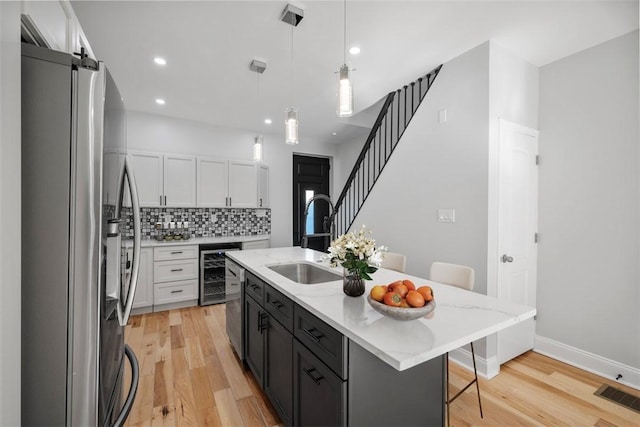 kitchen with a breakfast bar, decorative light fixtures, an island with sink, white cabinets, and stainless steel appliances