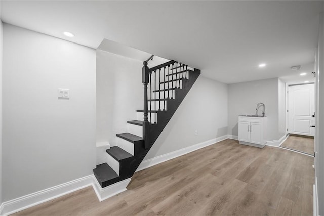 staircase with wood-type flooring and sink