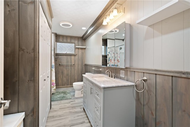 bathroom with vanity, hardwood / wood-style floors, wooden walls, and toilet