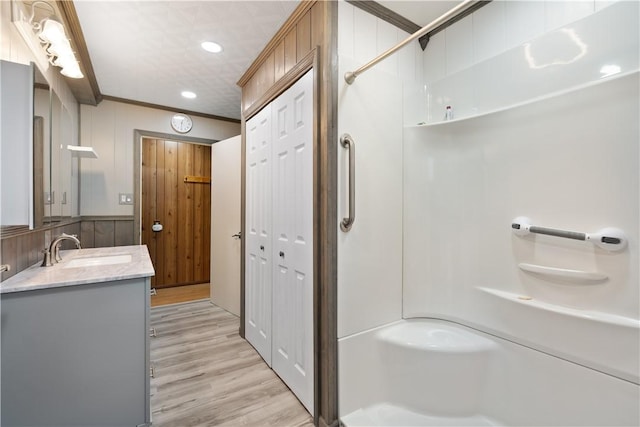 bathroom featuring vanity, crown molding, wood-type flooring, and a shower