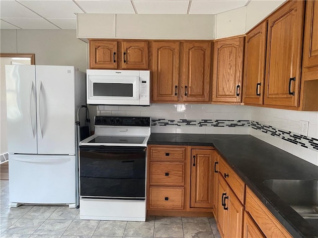 kitchen with sink, a paneled ceiling, backsplash, and white appliances