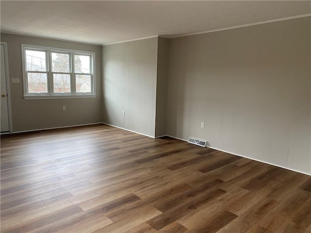 empty room featuring hardwood / wood-style flooring and ornamental molding