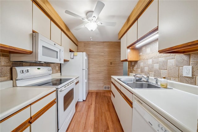 kitchen with white cabinetry, sink, white appliances, and light wood-type flooring