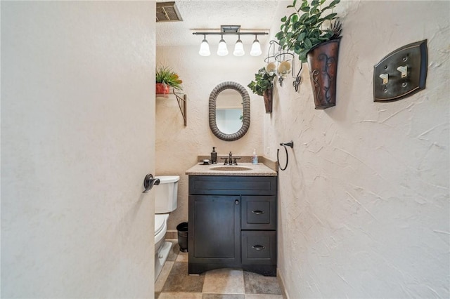 bathroom with vanity, toilet, and a textured ceiling