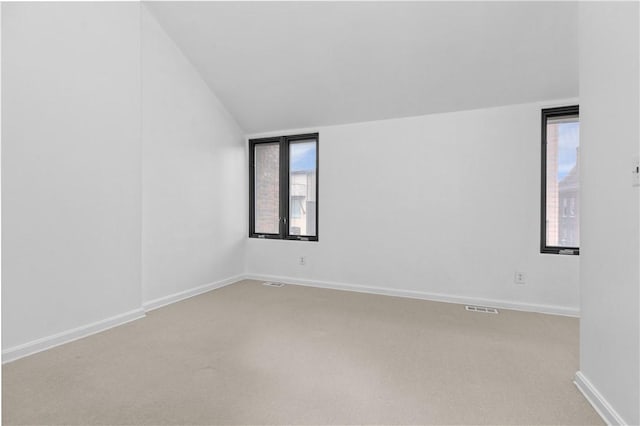 empty room with lofted ceiling, light carpet, and a wealth of natural light