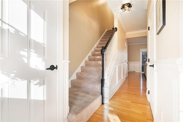 staircase with crown molding and wood-type flooring