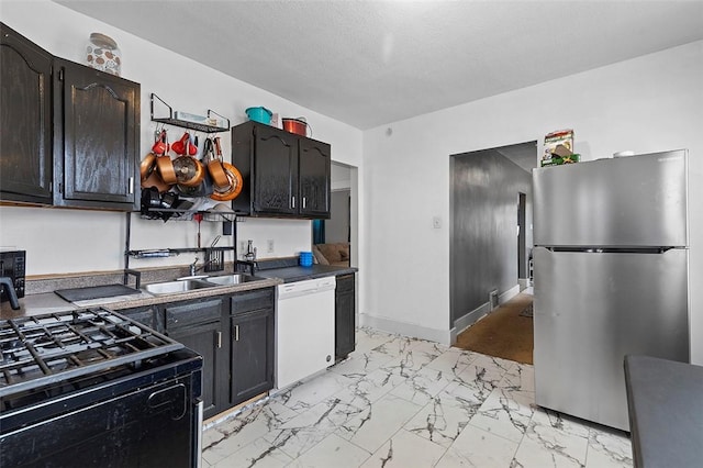 kitchen with sink, gas stove, a textured ceiling, stainless steel refrigerator, and dishwasher