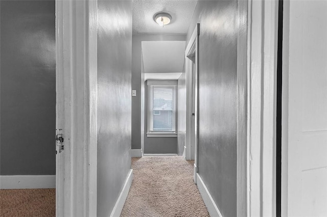 corridor with light colored carpet and a textured ceiling