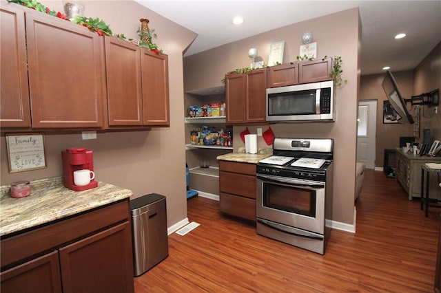 kitchen featuring appliances with stainless steel finishes, light stone counters, and light hardwood / wood-style flooring