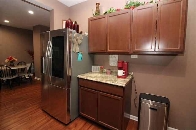 kitchen with dark wood-type flooring, light stone counters, and stainless steel refrigerator