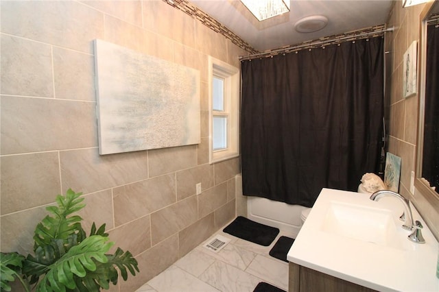 bathroom featuring vanity, tile walls, and shower / bathtub combination with curtain