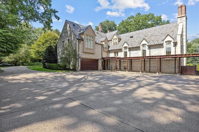 134 S Dr, Fox Chapel, PA 15238 - view of side of property featuring a chimney, a high end roof, stone siding, concrete driveway, and an attached garage