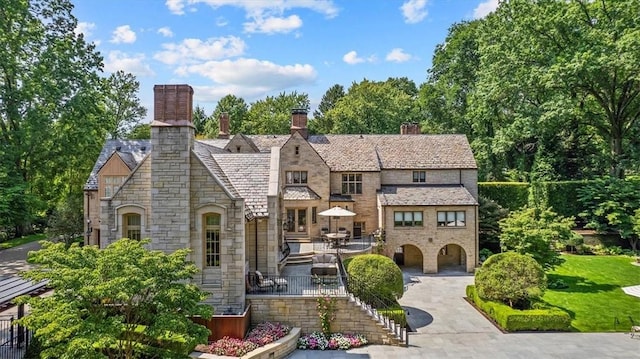 134 S Dr, Fox Chapel, PA 15238 - tudor-style house featuring stone siding, a high end roof, a chimney, a patio area, and stairway