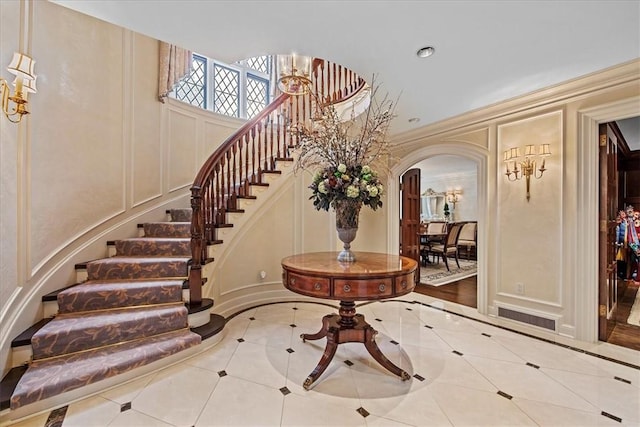 134 S Dr, Fox Chapel, PA 15238 - foyer entrance with a decorative wall, arched walkways, inlaid floor details, stairway, and tile patterned floors