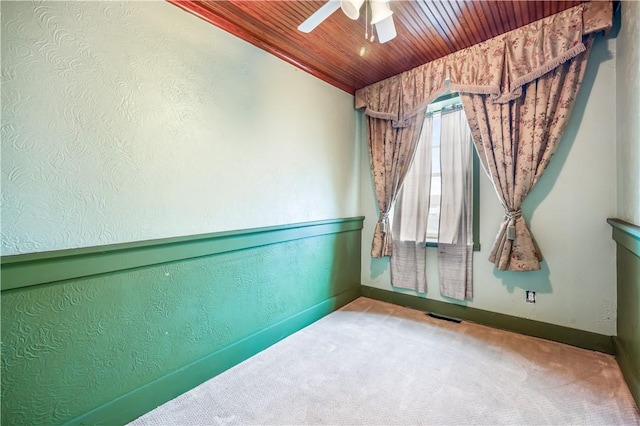 empty room with wood ceiling, ceiling fan, and carpet floors