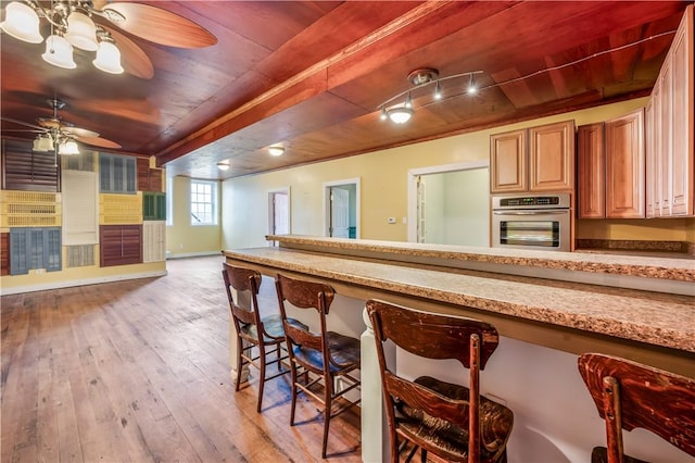 kitchen featuring ceiling fan, light stone countertops, wooden ceiling, oven, and light wood-type flooring