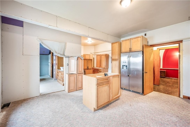 kitchen with a kitchen island, stainless steel refrigerator with ice dispenser, light carpet, and light brown cabinets