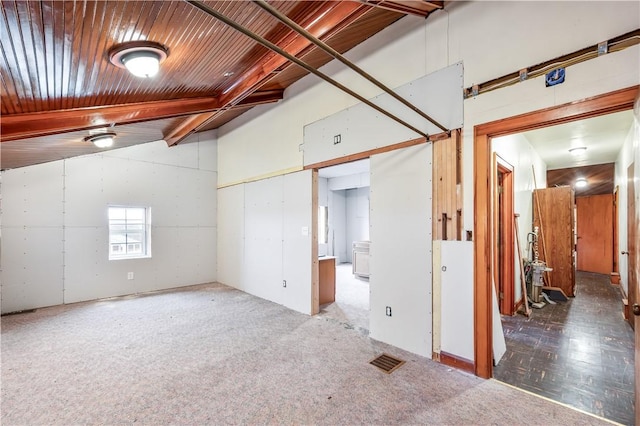 carpeted empty room with vaulted ceiling with beams and wooden ceiling